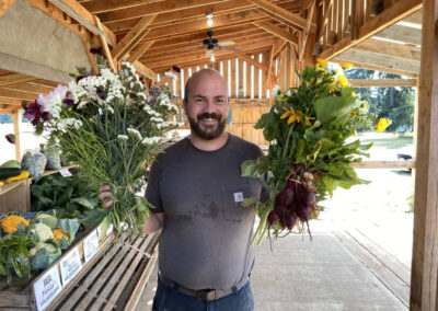 Man with massive u-pick flower bouquets, and beets